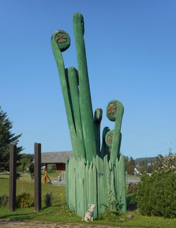 Dog in front of world’s largest fiddleheads in Plaster Rock, New Brunswick